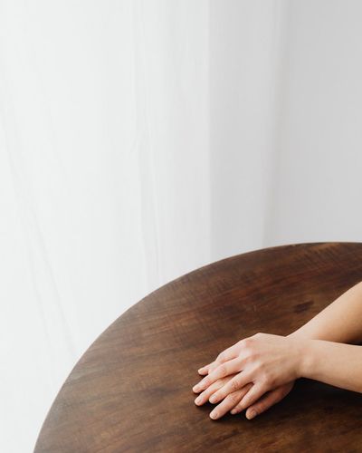 Close-up on hands gently resting on a wooden table.